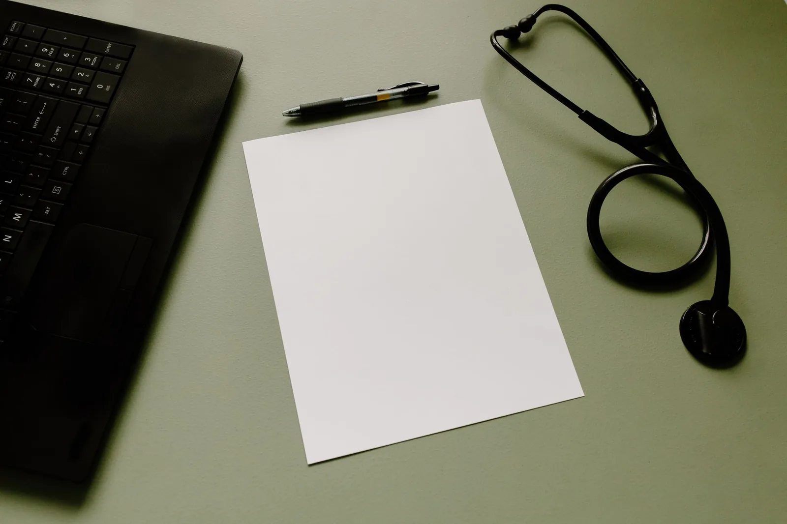 Mesa de consulta con documentos y portátil en clínica pequeña